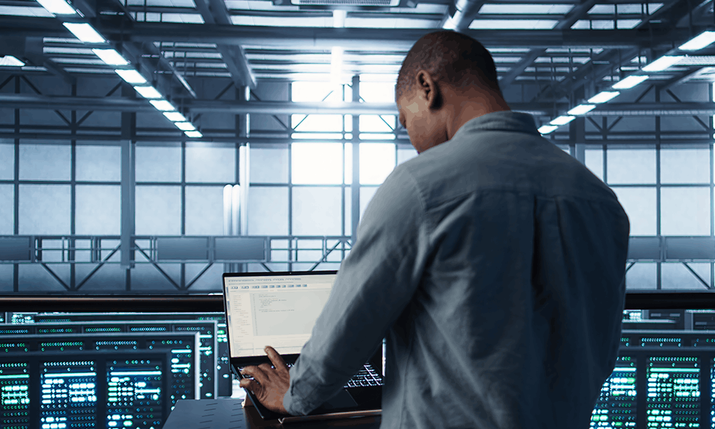 persona de espaldas trabajando en cuarto de servidores